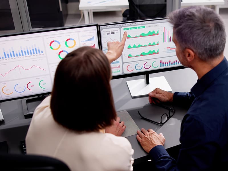 man and a woman sitting at a desk in front of a computer screen